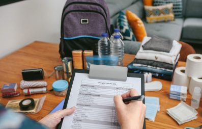 Unrecognizable woman doing checklist of emergency backpack in the living room